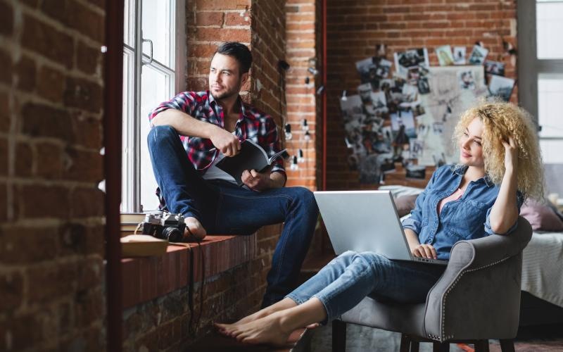 a man and a woman sitting with a laptop near a window